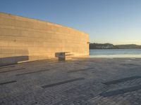 a curved concrete building with benches on the top and two smaller stone buildings below it