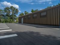 a metal building with a corrugated door in front of it and trees lining the street behind it