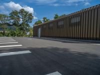 a metal building with a corrugated door in front of it and trees lining the street behind it