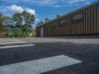 a metal building with a corrugated door in front of it and trees lining the street behind it