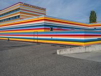 an empty parking lot painted brightly stripes on the wall of the building and sky as well as stones