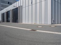 an industrial building with four metal doors and two drainage covers on either side of the walkway