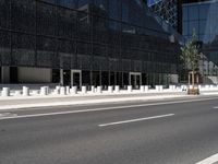 a paved road with black buildings and glass windows on it in front of a large building