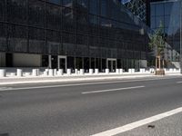 a paved road with black buildings and glass windows on it in front of a large building