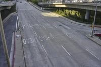 empty freeway with graffiti written on the side, on either side of a freeway and one lane