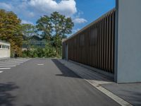 a metal building with a corrugated door in front of it and trees lining the street behind it