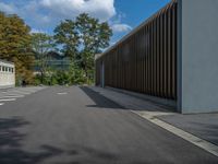 a metal building with a corrugated door in front of it and trees lining the street behind it