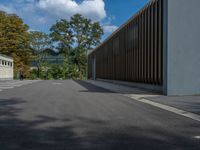 a metal building with a corrugated door in front of it and trees lining the street behind it