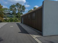 a metal building with a corrugated door in front of it and trees lining the street behind it