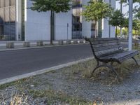 a park bench by the side of a road near a building with a large window