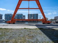 a man is sitting under the big orange structure at a boat dock on a lake