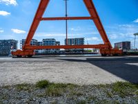 a man is sitting under the big orange structure at a boat dock on a lake