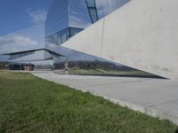 a person walking in front of a modern building, with grass on the side of the walkway