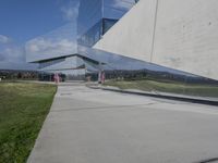 a person walking in front of a modern building, with grass on the side of the walkway