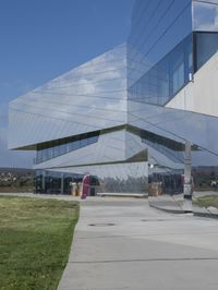 a person walking in front of a modern building, with grass on the side of the walkway