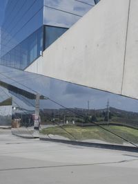 a person walking in front of a modern building, with grass on the side of the walkway