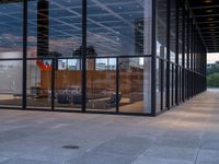 a room with glass walls and an office window, with chairs outside and in the background