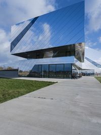 a young woman walks past the glass walls of an office building near a grassy area