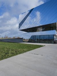 a young woman walks past the glass walls of an office building near a grassy area