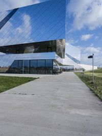 a young woman walks past the glass walls of an office building near a grassy area