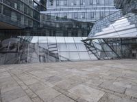 a courtyard that features a glass building with many large windows and a reflection on the wall