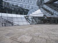 a courtyard that features a glass building with many large windows and a reflection on the wall