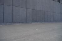 a person wearing a face mask walking across an empty street with a skateboard in the foreground