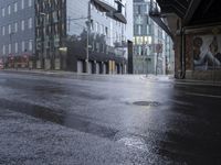 a wet street that looks like it's raining down from the sky and in front of buildings