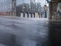 a wet street that looks like it's raining down from the sky and in front of buildings