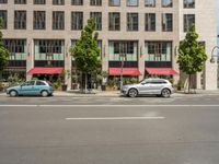 cars and pedestrians are parked at the curb in front of an older office building that is surrounded by modern architecture