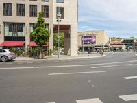 cars and pedestrians are parked at the curb in front of an older office building that is surrounded by modern architecture