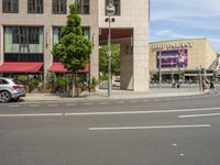 cars and pedestrians are parked at the curb in front of an older office building that is surrounded by modern architecture