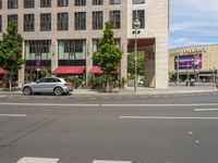 cars and pedestrians are parked at the curb in front of an older office building that is surrounded by modern architecture