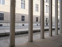 a long cement walkway next to a tall building with several doors and windows on each side