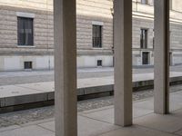 a long cement walkway next to a tall building with several doors and windows on each side