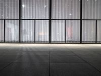 a empty room in a large building with sheer curtained windows overlooking the city on a cloudy day