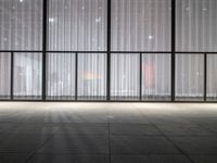 a empty room in a large building with sheer curtained windows overlooking the city on a cloudy day