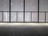 a empty room in a large building with sheer curtained windows overlooking the city on a cloudy day