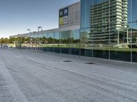 view of an office building from a glass facade with the reflection on it, and an empty parking lot in front, which is clear