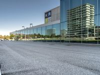 view of an office building from a glass facade with the reflection on it, and an empty parking lot in front, which is clear