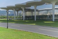 the paved path in front of a glass building that has curved arches on each side