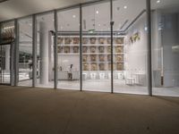 the inside of a glass walled room with lots of glass doors and shelves that are white