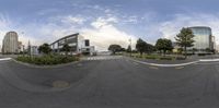 a fisheye lens photo of an empty street in a city with tall buildings in the background