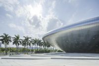 a building that has many palm trees around it and the sun in front of it