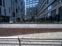 there is an empty bench along the brick path in the city area of the building