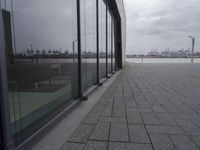 a row of benches sits outside of a large glass building with a cityscape view