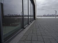a row of benches sits outside of a large glass building with a cityscape view