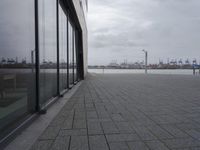a row of benches sits outside of a large glass building with a cityscape view