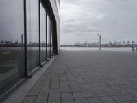 a row of benches sits outside of a large glass building with a cityscape view