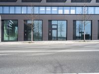 a black building with windows on the corner, and a stop sign at an intersection